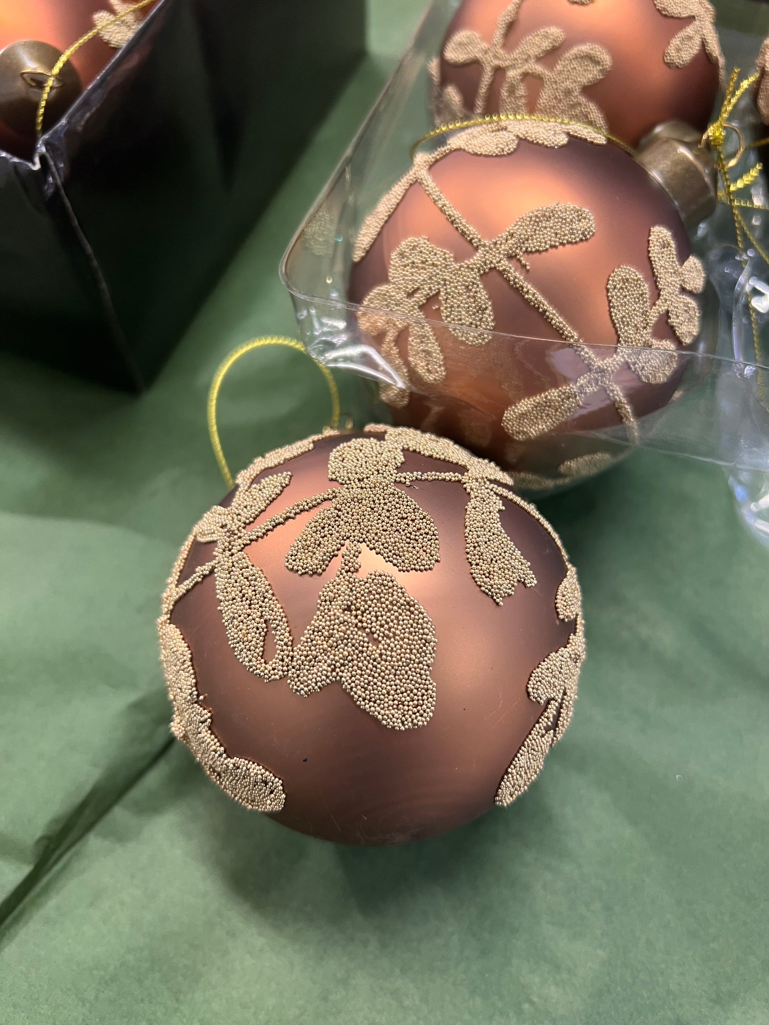 Pronssin värinen joulupallo kultaisella lehtikuviolla