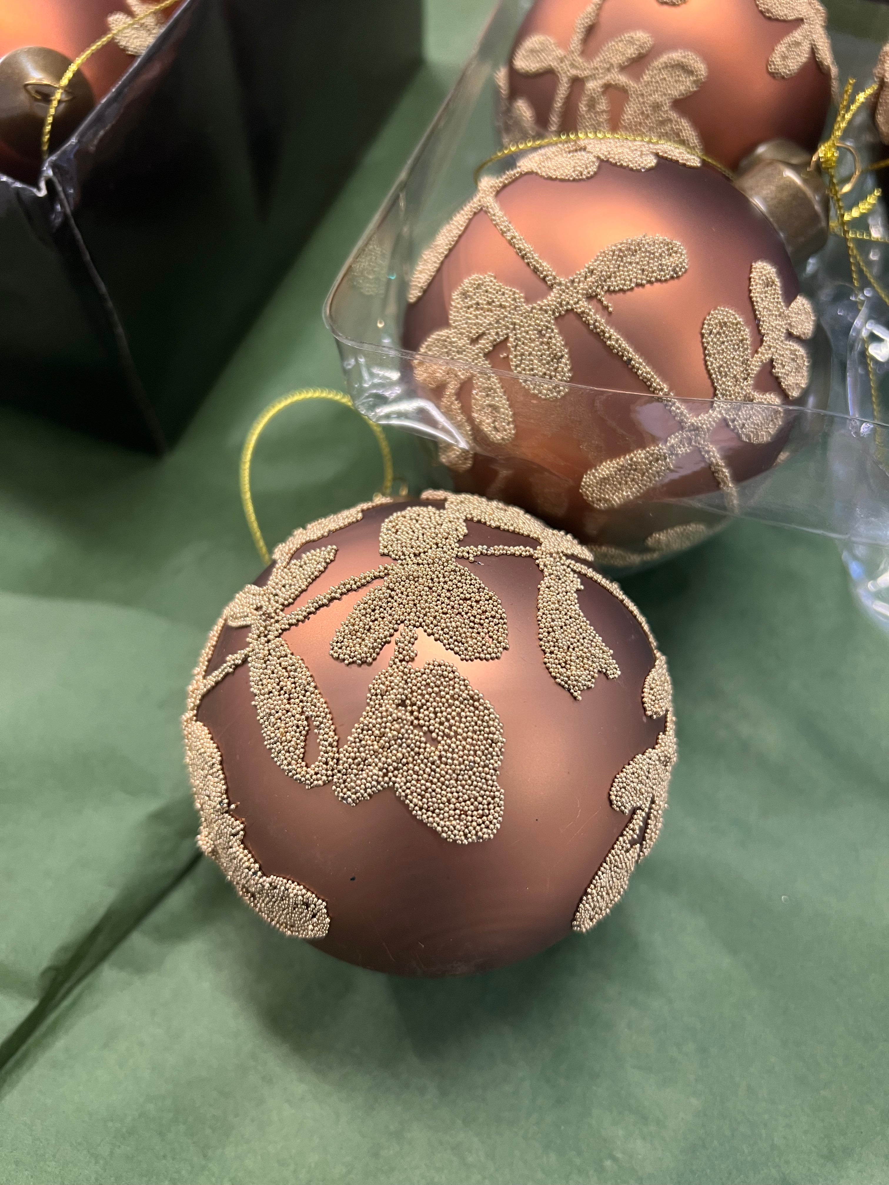 Pronssin värinen joulupallo kultaisella lehtikuviolla